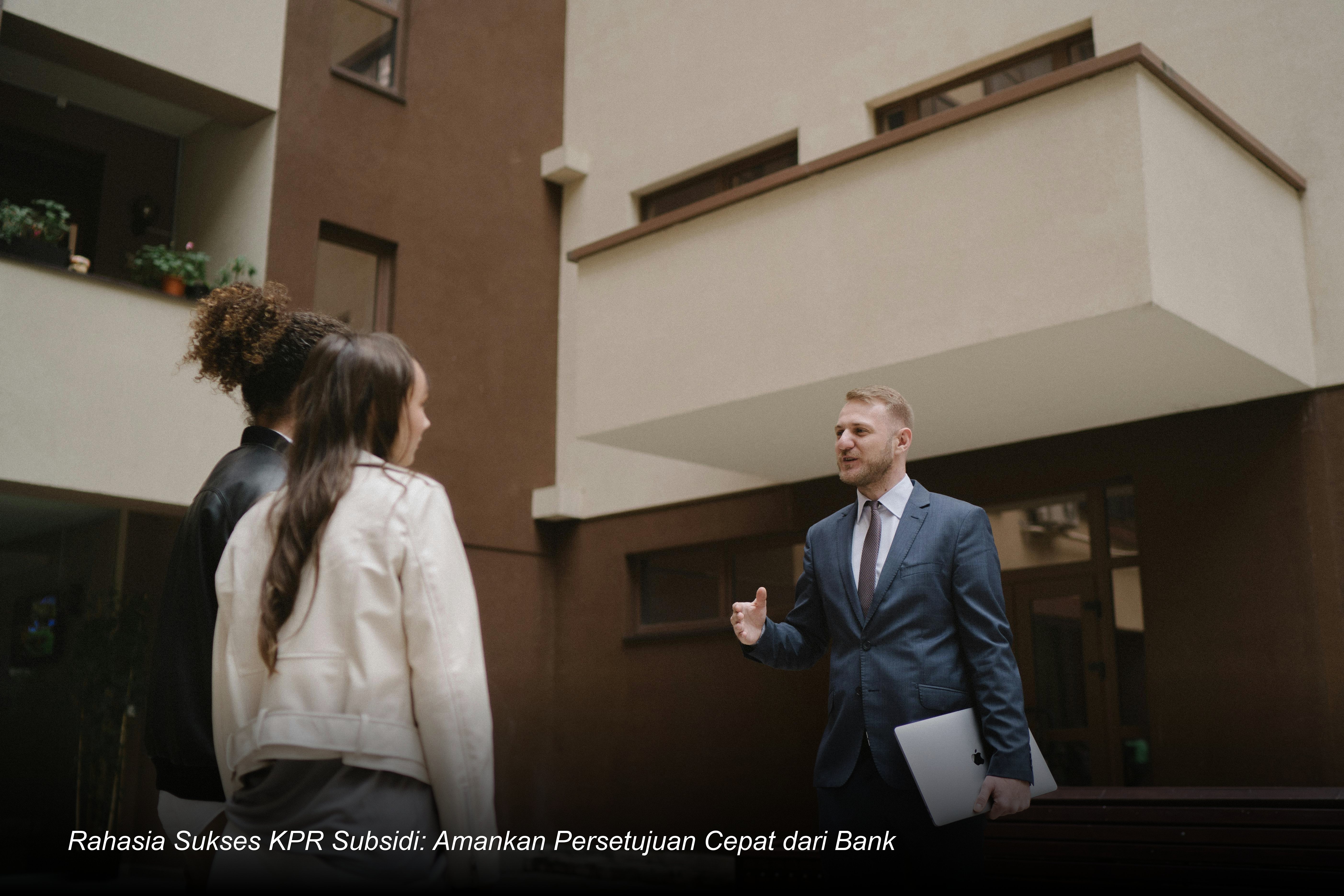 Seorang pasangan muda terlihat bahagia saat menandatangani dokumen akad kredit KPR di hadapan petugas bank dengan latar belakang miniatur rumah minimalis.