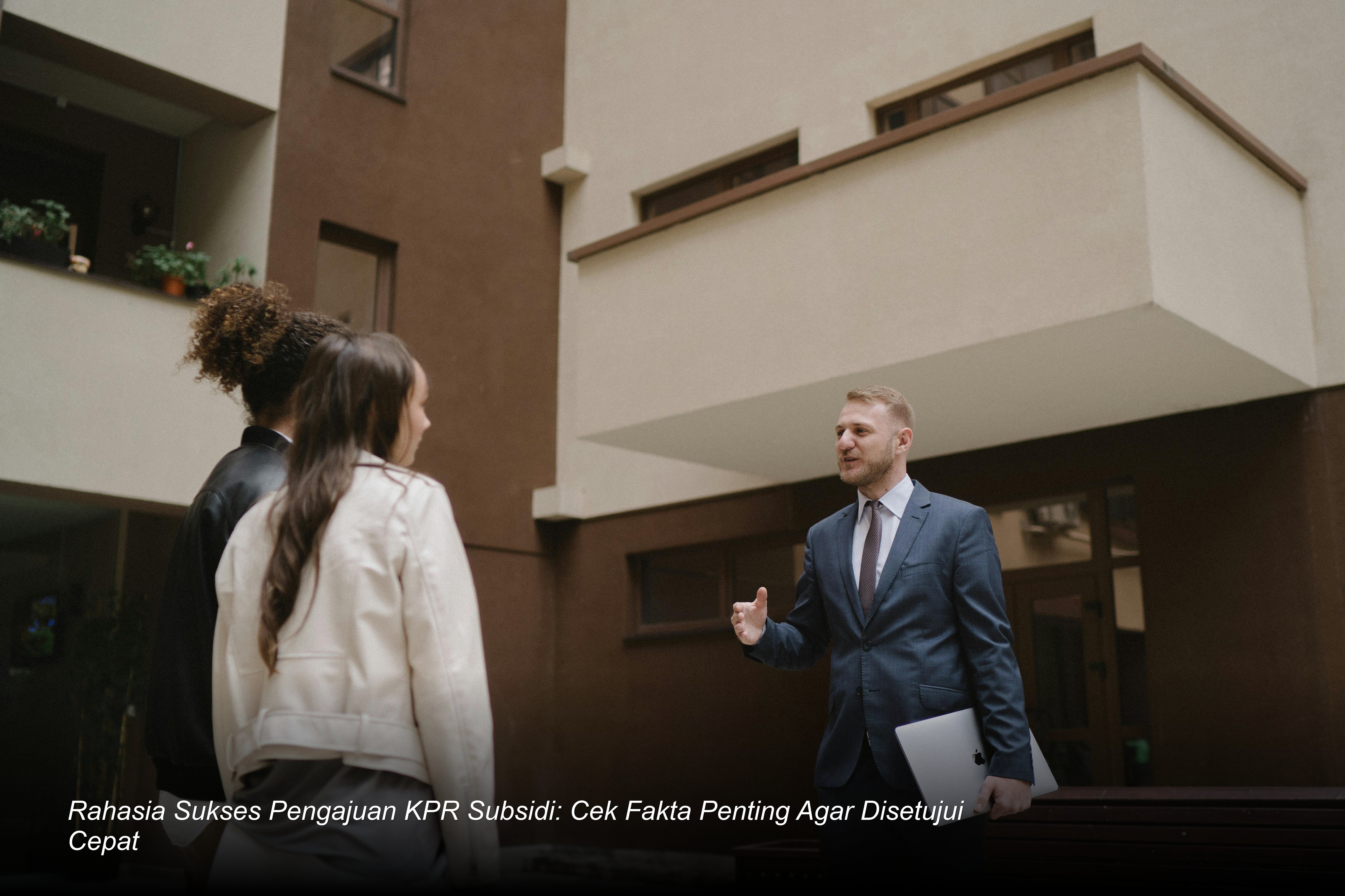 Seorang profesional bank tersenyum saat menyerahkan kunci rumah minimalis modern kepada pasangan muda yang baru saja menandatangani akad kredit.