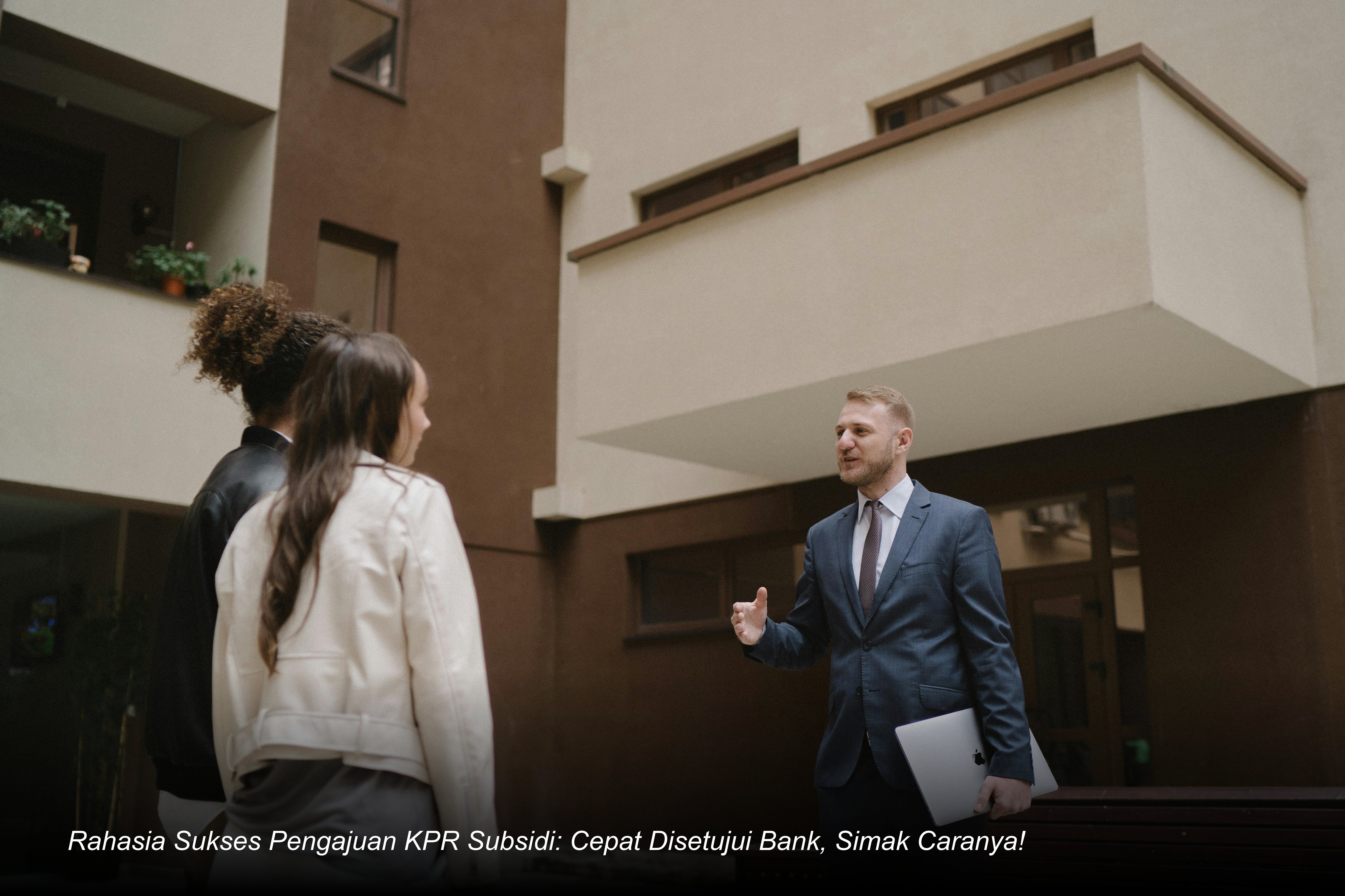 Seorang pasangan muda tersenyum bahagia saat menandatangani dokumen akad kredit KPR Subsidi di hadapan notaris dan petugas bank.